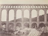 an old photo of a train going under a bridge