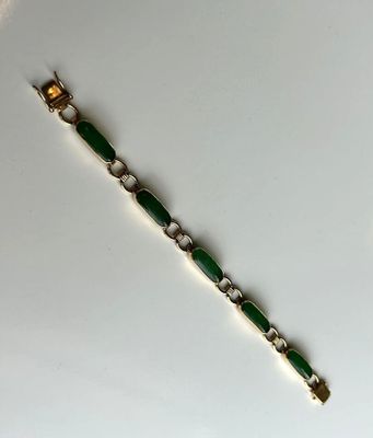 un gros plan d'un bracelet vert posé sur une surface blanche