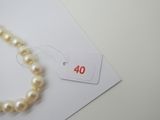 un collier de perles blanches avec une étiquette de prix posée sur un morceau de papier