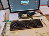 a computer on a desk with papers and a keyboard