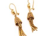 une paire de boucles d'oreilles en or ornées de pompons sur fond blanc