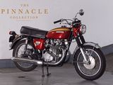 a red motorcycle parked in front of a white wall