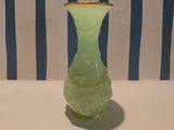 a green vase with a gold rim sitting on a table