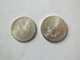 two silver coins sitting next to each other on a white surface