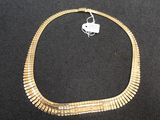 gold plated necklace on a black background with a white tag