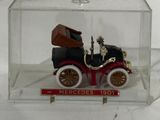 a small toy car in a clear box on a white surface