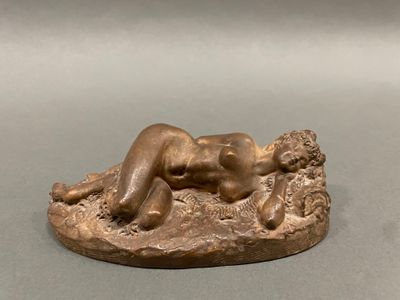 bronze statue of a woman laying on a rock with her legs crossed