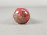 a picture of a red and gold bead on a white surface