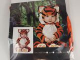 a close up of a baby in a tiger costume on a white surface