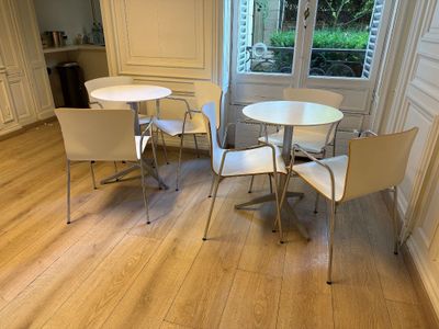 une table et des chaises blanches dans une pièce dotée d'une fenêtre
