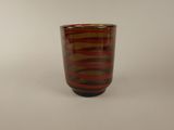 a red and black striped glass cup on a white surface