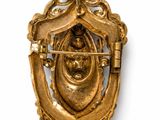 an image of a gold broochle with a face on it