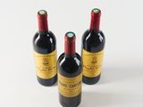 three bottles of red wine sitting on top of a white surface