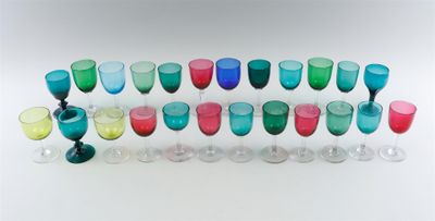 many different colored glasses lined up on a white surface