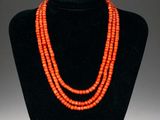 an orange beaded necklace on a black mannequin