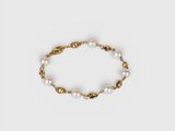 a gold bracelet with pearls on a white background