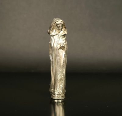 an old silver figurine of a woman with a veil on her head