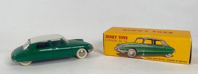 green toy car in front of a yellow box on a white surface