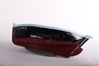 a red and black boat sitting on top of a white surface