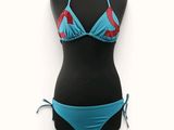 un gros plan sur un bikini posé sur un mannequin, avec un haut de bikini bleu et rouge
