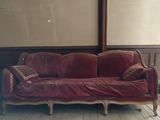a red couch sitting in a room with a wooden floor