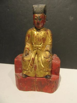 a gold statue of a man sitting on a red chair