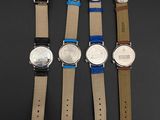 four watches are lined up in a row on a black surface