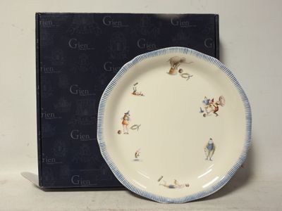 une assiette bleue et blanche décorée d'oiseaux, à côté d'une boîte noire