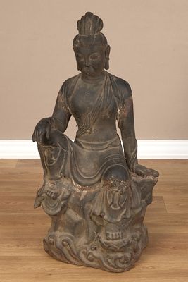 statue of a seated buddha sitting on a rock on a hard wood floor