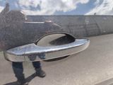a reflection of a person standing in the reflection of a car door handle