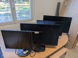 three computer monitors sitting on a desk in front of a window