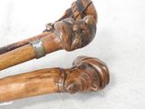 two wooden canes with carvings on them on a white surface