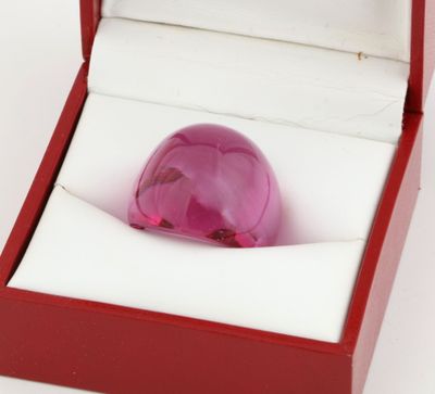 a pink glass ball in a red box on a white surface