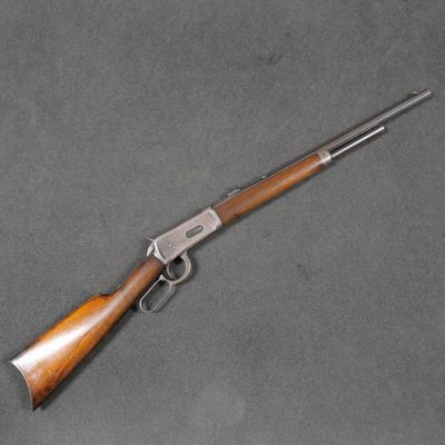 un fusil Winchester avec une crosse en bois et un canon plaqué argent