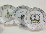 several plates and cups are sitting on a stand on a white surface