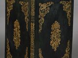 an old black and gold book sitting on top of a table