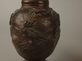 a brown vase with a bird on it sitting on a table