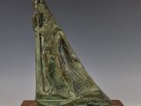 sculpture en bronze représentant une femme dans un bateau, posée sur un socle en bois
