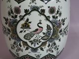 a white vase with a bird and flowers on it