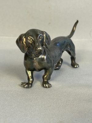 a small bronze dog statue on a white surface