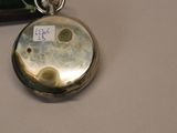a silver pocket watch on a table next to a mirror