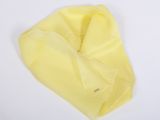 L'écharpe jaune est posée sur une surface blanche.