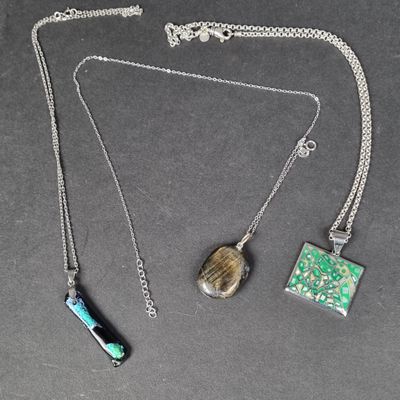 three pieces of jewelry are displayed on a black surface