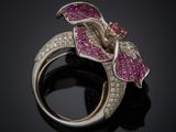 a close up of a ring with pink stones on a black surface
