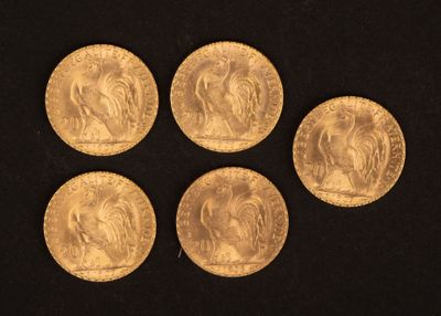 six souverains d'or de tailles et de formes variées sur un fond noir