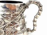a silver pitcher with a bamboo handle on a white background
