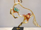 sculpture représentant un cheval au galop, avec des fleurs sur le dos, posée sur un socle en marbre