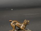 bronze figurine of a dog on a pedestal on a gray surface