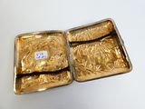two pieces of gold are in a metal case on a white surface