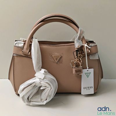 un sac à main en cuir beige avec un foulard blanc posé sur une table blanche
